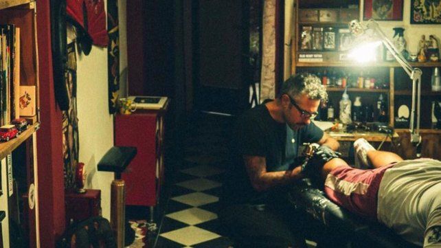 Bruno Zek tatuando una pantorrilla bien lejos de la zona de contagios.