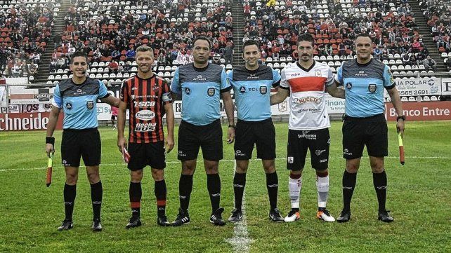 Nicolás Domingo, el capitán de Patronato, junto a Maximiliano Coronel, de Deportivo Morón, y la terna arbitral.