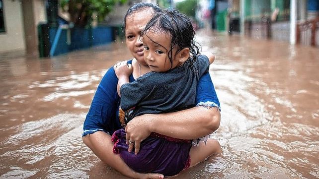 Una mujer carga a su hija tratando de ponerse a salvo durante las inundaciones en Yakarta, Indonesia Una mujer carga a su hija tratando de ponerse a salvo durante las inundaciones en Yakarta, Indonesia