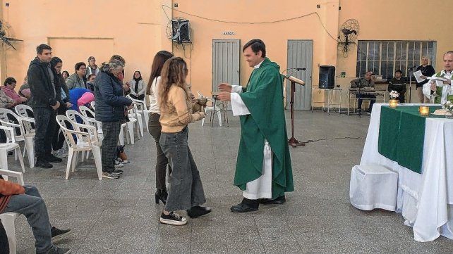 Con dificultad. Candela, con una bota en la pie izquierdo, lleva las ofrendas junto a su madre en la misa del domingo.
