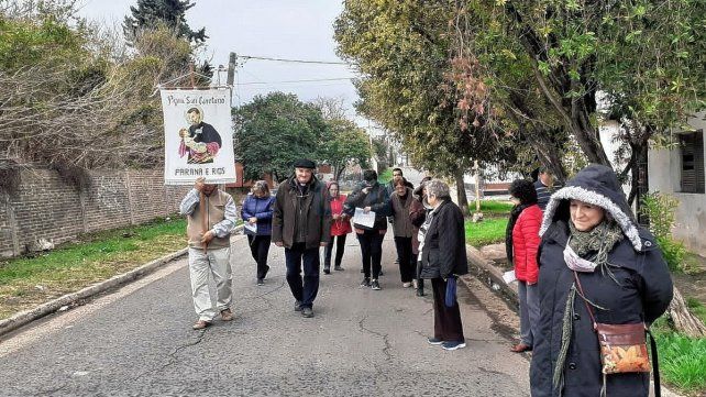 Caminar. El sacerdote y parte de la comunidad, recorren las calles de los barrios lindantes a la parroquia para invitar a los vecinos a sumarse a la preparación espiritual para el próximo 7 de agosto.
